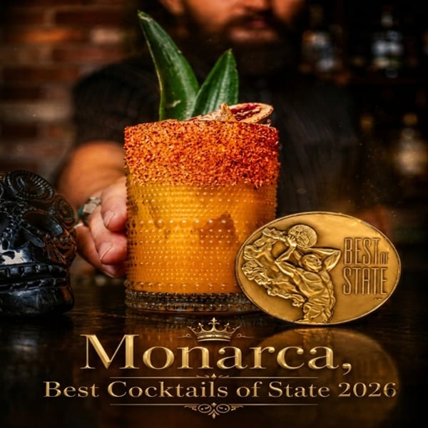 Bartender holding a Monarca cocktail with a chili-lime rim, pineapple leaves, and a "Best of State" medal.